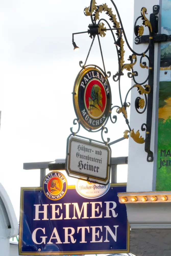 Das Heimer und Paulaner Biergartenschild welches an der Ecke der Zeltfront hängt.